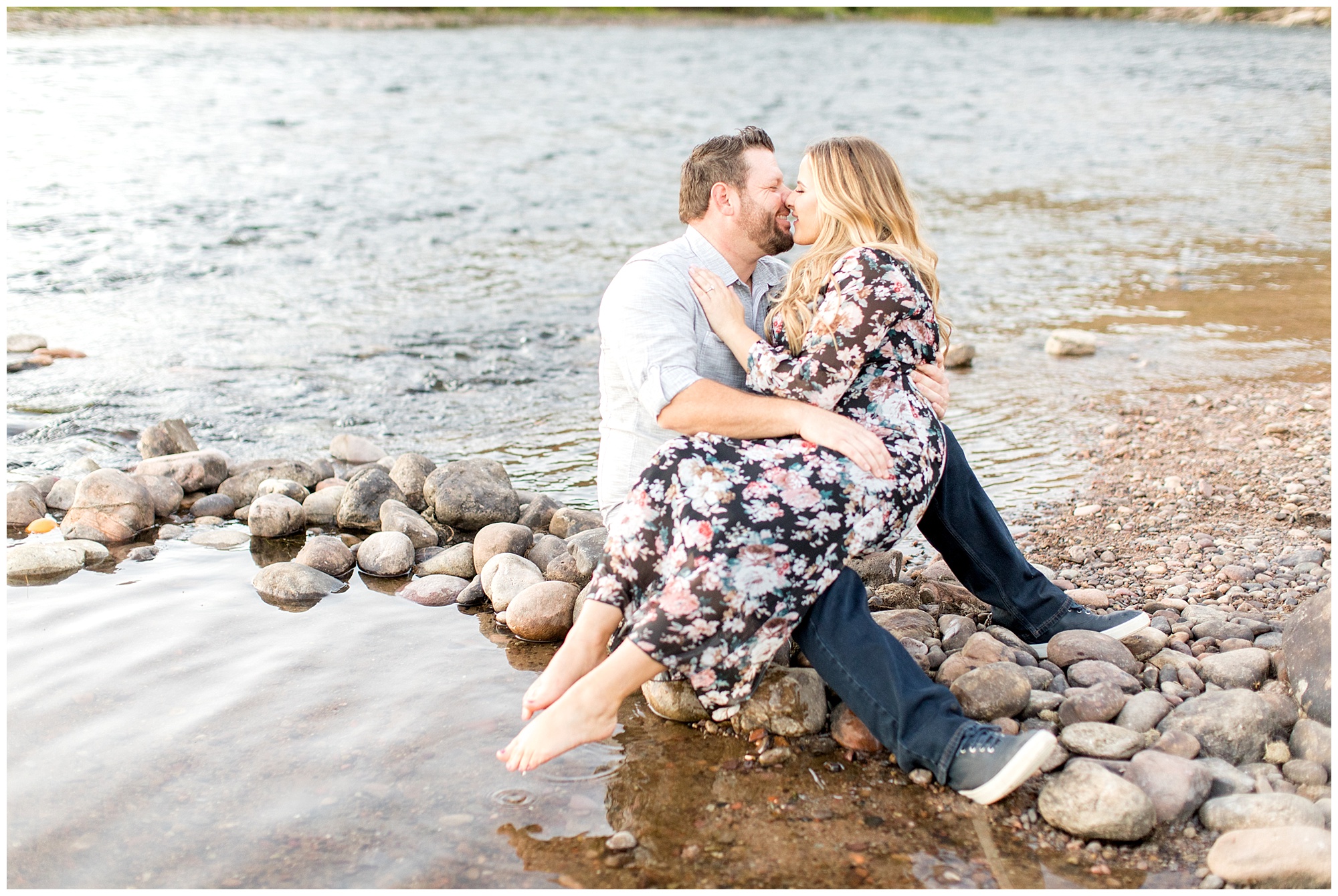 bride sitting on grooms lap at edge of pebble beach at salt river in mesa az during engagement session