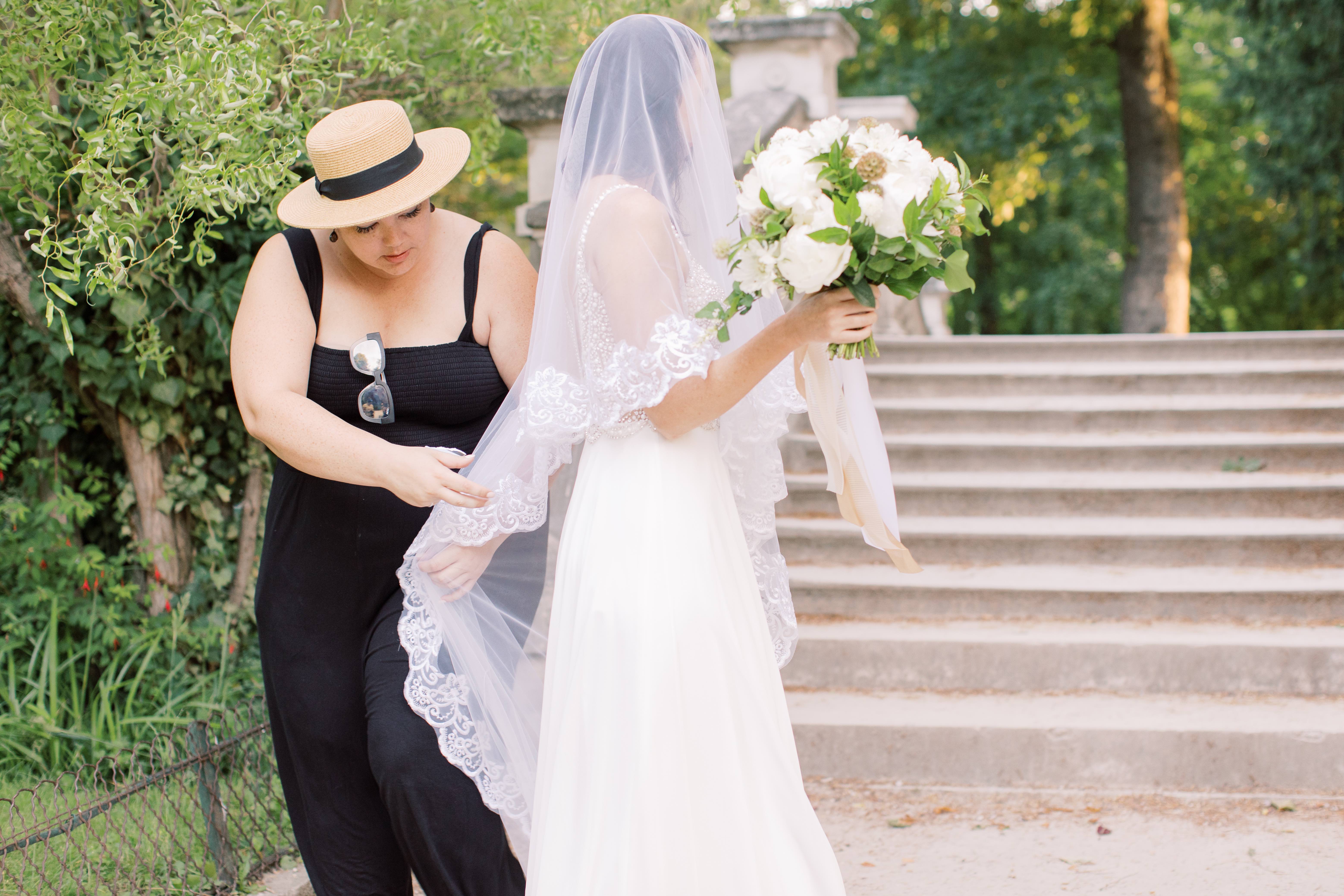 head Arizona wedding planner Ashley from your jubilee helping adjust a brides veil in Paris