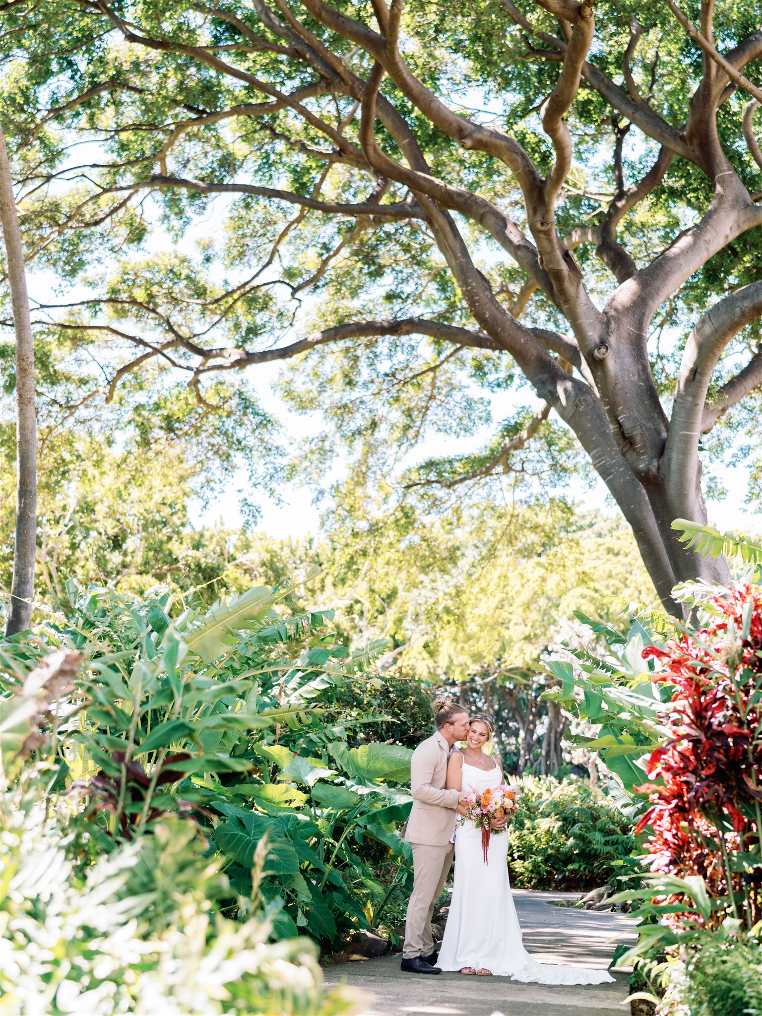 bride and groom share an embrace under the lush greenery of the Hawaiian island, Maui